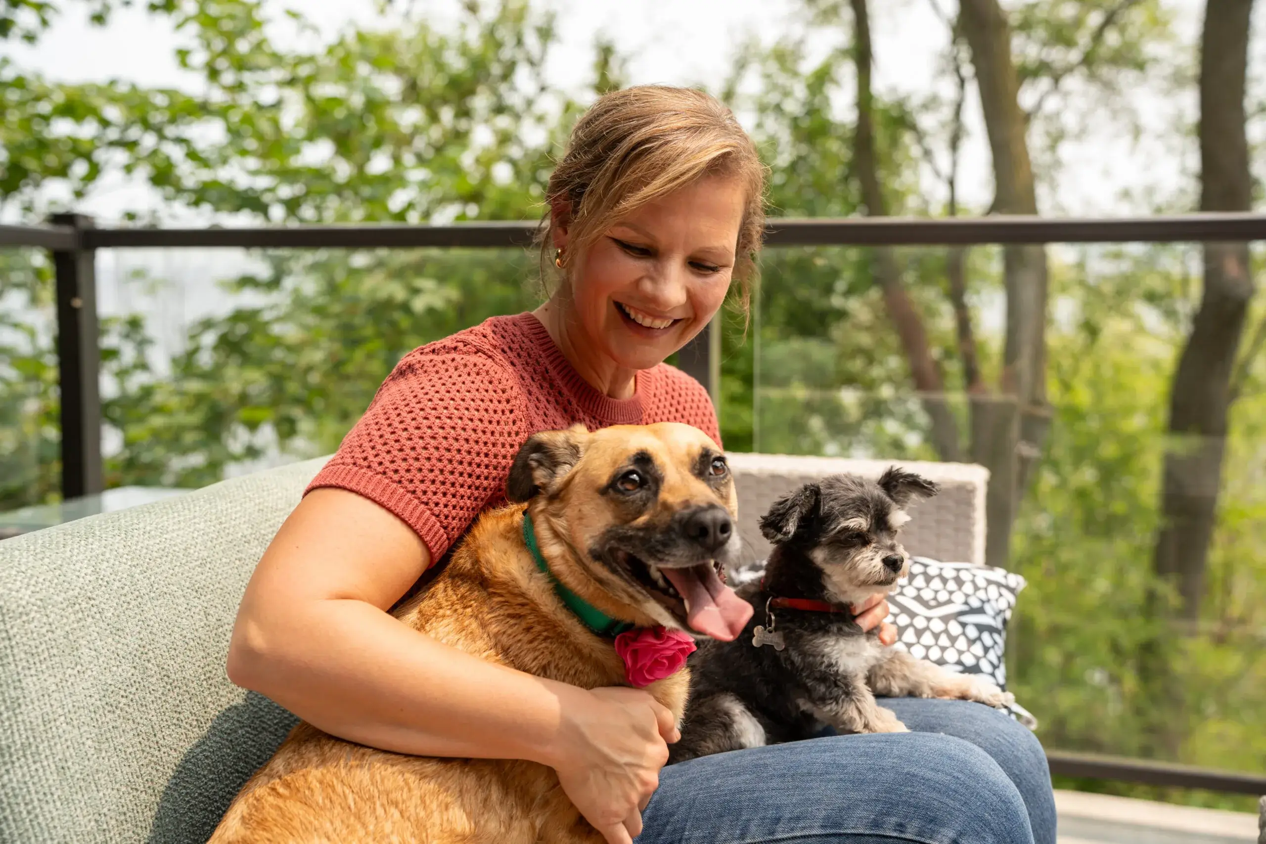 A woman smiling and holding two small dogs